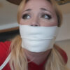 Blonde woman looking upward with wide eyes while tightly gagged under thick white microfoam tape covering her mouth