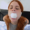 Redhead woman with eyes closed and freckles, mouth stuffed with white socks and sealed under clear tape wrapped around her head