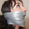 Dark-haired woman in side profile with thick silver duct tape wrapped tightly over her mouth